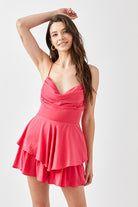 A young woman confidently poses in a chic, tiered romper with a flattering cowl neckline. The lightweight fabric drapes elegantly, creating a flowy silhouette as she moves. She pairs the romper with strappy heels and delicate jewelry, exuding effortless style. The look is perfect for a night out, date night, or special event, blending sophistication with a trendy, feminine touch.