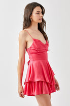 A young woman confidently poses in a chic, tiered romper with a flattering cowl neckline. The lightweight fabric drapes elegantly, creating a flowy silhouette as she moves. She pairs the romper with strappy heels and delicate jewelry, exuding effortless style. The look is perfect for a night out, date night, or special event, blending sophistication with a trendy, feminine touch.