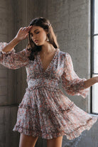 Model wearing fall floral ruffle mini dress with balloon sleeves, V-neck, and tiered design in a boho-chic style, perfect for autumn outfits