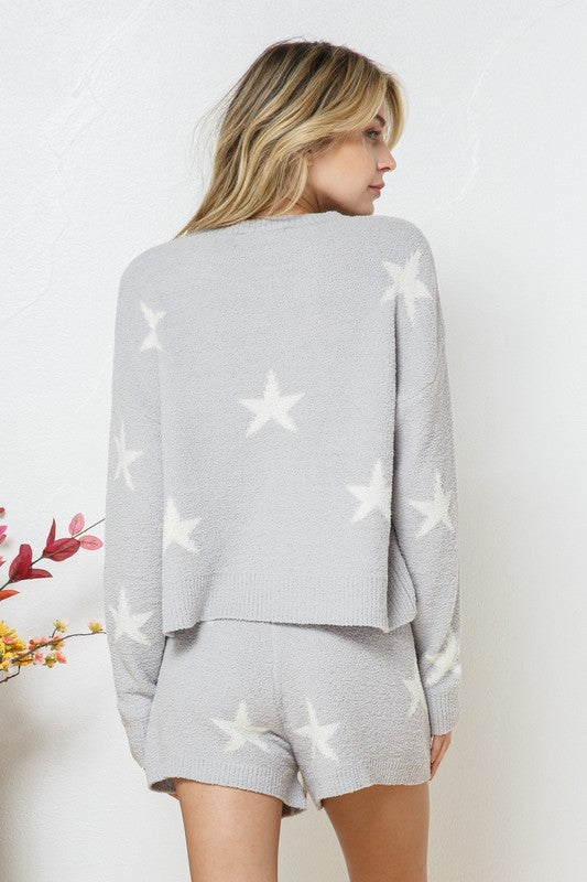 Model wearing a cozy grey lounge set with a star print design. The set includes a relaxed-fit, long-sleeve top with white star accents and matching drawstring shorts, perfect for comfortable and stylish loungewear