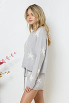 Model wearing a cozy grey lounge set with a star print design. The set includes a relaxed-fit, long-sleeve top with white star accents and matching drawstring shorts, perfect for comfortable and stylish loungewear