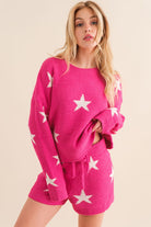 Model wearing a cozy hot pink lounge set with a star print design. The set includes a relaxed-fit, long-sleeve top with white star accents and matching drawstring shorts, perfect for comfortable and stylish loungewear